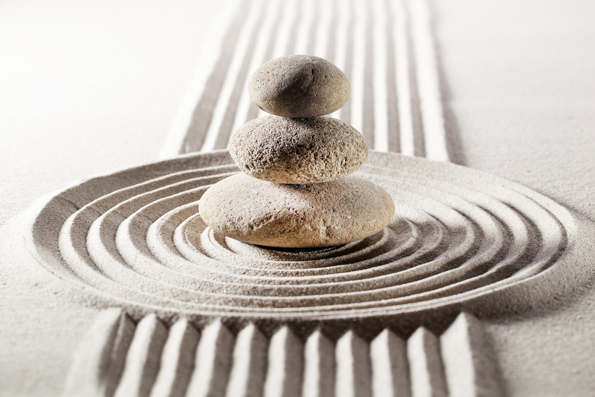 Image zen avec des galets et des ronds sur le sable, représentant la détente.